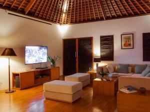a living room with a couch and a flat screen tv at Villa The Beji in Canggu