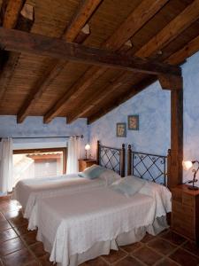 2 camas en un dormitorio con paredes azules y techos de madera en Casa Rural El Encuentro, en Villalón de Campos