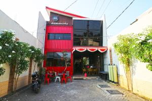 a red building with tables and chairs in front of it at Kamariska Hostel in Sedati