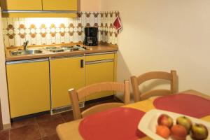 ペルツァーハケンにあるAppartements Am Waldrandのキッチン(黄色のキャビネット、フルーツプレート付きのテーブル付)