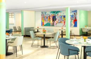 Queen Elizabeth 2 Hotel في دبي: مطعم بطاولات وكراسي و لوحة على الحائط