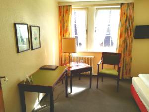 ein Hotelzimmer mit einem Schreibtisch, einem Bett und einem Tisch in der Unterkunft Hotel Krohwinkel in Hittfeld