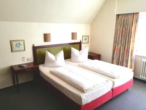 a hotel room with a large bed with white pillows at Hotel Krohwinkel in Hittfeld