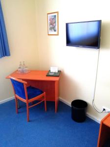 a room with a table and a chair and a television at Hotel Krohwinkel in Hittfeld