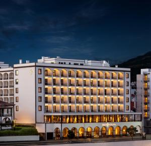 een groot wit gebouw met verlichting aan bij Grand Hotel Açores Atlântico in Ponta Delgada
