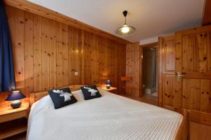 1 dormitorio con paredes de madera y 1 cama con 2 lámparas en Apartment Batteuse en Grimentz