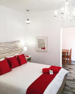 a bedroom with a large white bed with red pillows at Esmarline Lodge in Brits