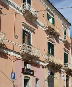 un edificio rosa con balconi e un cartello sopra di B&B Palazzo Rochira a Castellaneta