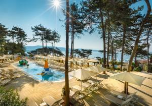 a swimming pool with chairs and umbrellas at Valamar Camping Ježevac in Krk