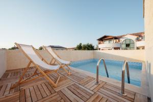 a pair of chairs sitting on a deck next to a swimming pool at Villa Privlaka in Privlaka