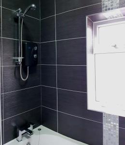 a black tiled bathroom with a shower and a sink at Prosecco Palace in York