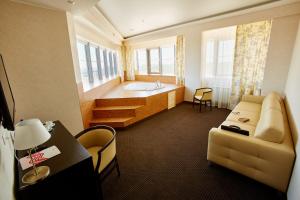 ein Hotelzimmer mit einem Sofa und einer Badewanne in der Unterkunft Spa Hotel Meliot in Tscheljabinsk
