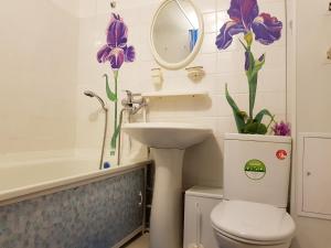 スタールイ・オスコルにあるКвартира на Королеваのバスルーム(トイレ、シンク付)が備わります。紫色の花を飾っています。