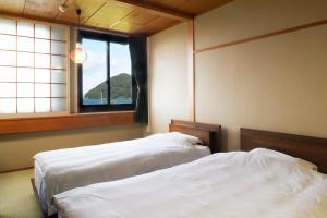 two beds in a room with a window at Yadoya Tsubaki in Aomori