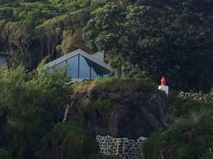een huis op een klif met een rode vuurtoren bij T2 Lux Casa das Pereiras in Calheta de Nesquim