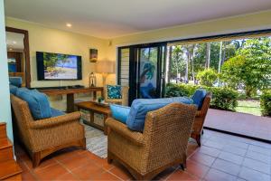 a living room with wicker chairs and a television at Number 2 On The Beach | Beautiful Beachfront Villa in Port Douglas