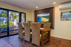 a dining room with a wooden table and wicker chairs at Number 2 On The Beach | Beautiful Beachfront Villa in Port Douglas