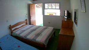 a bedroom with two beds and a dresser and a window at Pousada Águas Formosas in Ubatuba