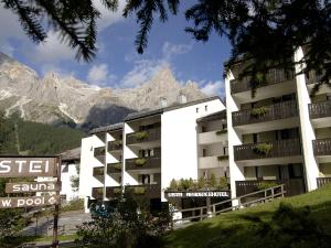 a white building with a mountain in the background at Residence Lastei in San Martino di Castrozza