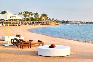 uma praia com bancos e guarda-sóis e a água em Steigenberger Pure Lifestyle (Adults Only) em Hurghada