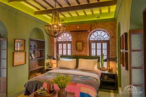 ein Schlafzimmer mit einem Bett in einem Zimmer mit Fenstern in der Unterkunft Calcutta Bungalow in Kalkutta