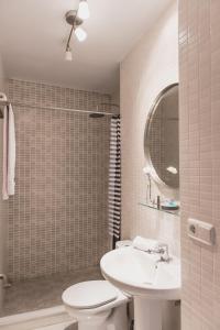 een badkamer met een wastafel, een toilet en een spiegel bij Arenal Maestranza Apartment in Sevilla
