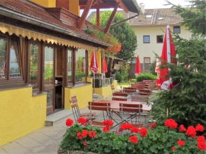 a row of tables and chairs with umbrellas and flowers at Hotel Alp Inn in Ruhpolding