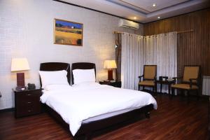 a bedroom with a large white bed and two chairs at Safari Club 2 Bahria Town in Rawalpindi