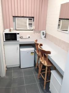 uma pequena cozinha com um balcão e duas cadeiras em Bananatown Motel em Coffs Harbour