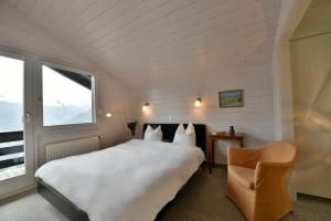 ein Schlafzimmer mit einem großen weißen Bett und einem Stuhl in der Unterkunft Chalet Mousseron in Grimentz