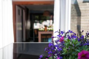 Un mazzo di fiori viola davanti a una porta. di Heerlijk Huis aan het IJsselmeer a Stavoren