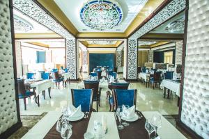 un restaurant avec des tables et des chaises et un lustre dans l'établissement Emerald Hotel Baku, à Baku