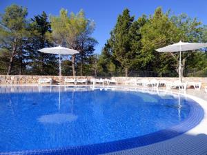 a swimming pool with chairs and umbrellas at Camping Paklenica in Starigrad-Paklenica