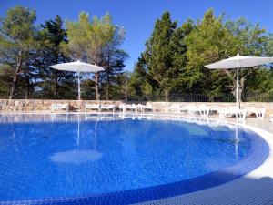 a swimming pool with chairs and umbrellas at Camping Paklenica in Starigrad