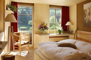 a bedroom with a bed and a desk and windows at Bio-Hotel Helvetia in Bad Schandau