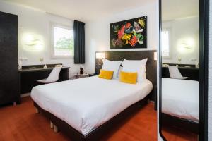 um quarto com uma grande cama branca com almofadas amarelas em Hôtel Restaurant Le Clos Fleuri em Castelnaudary