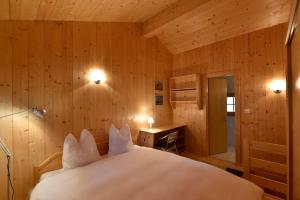 グリメンツにあるChalet Freschの木製の壁に白いベッドが備わるベッドルーム1室