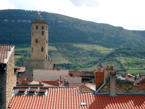 a building with a tower and a mountain in the background at Hôtel du Commerce - Centre Millau in Millau