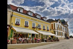 a yellow building with people sitting outside of it at Hotel Restaurant zur Post in Melk