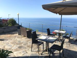 a patio with tables and chairs and an umbrella at Albergo Luna di Marzo in Volastra