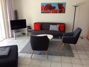 ein Wohnzimmer mit einem Sofa, Stühlen und einem TV in der Unterkunft Lido Golf in Ascona