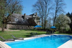 einen Pool mit Stühlen und Sonnenschirmen vor einem Haus in der Unterkunft B&B Chateau le Bois in Saint-Julien-aux-Bois