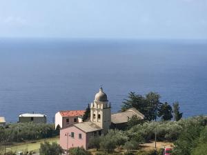 a building on a hill with the ocean in the background at Albergo Luna di Marzo in Volastra