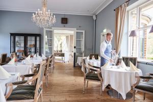 a man standing in a dining room with tables at Hotel Vejlefjord in Stouby