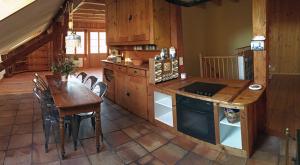 a kitchen with a wooden table and a table and chairs at La Cachotière in La Chaux-du-Milieu