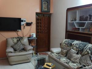 a living room with two chairs and a flat screen tv at Padmaa Hampi Villa in Hampi