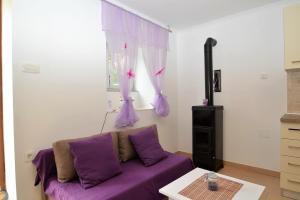 ein lila Sofa im Wohnzimmer mit Fenster in der Unterkunft Apartment Hrasta in Vrana