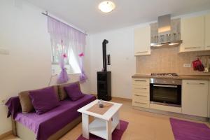 a living room with a purple couch and a kitchen at Apartment Hrasta in Vrana