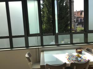 una mesa blanca y sillas en una habitación con ventanas en MyRoom Città Alta 2, en Bérgamo