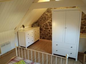 a attic bedroom with a bed and a dresser at Gîte à la Ville in Rostrenen